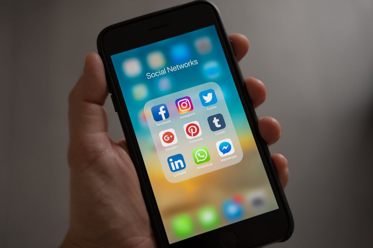 about-us-01 A smartphone displaying various social media icons held in a hand, showcasing modern communication apps.